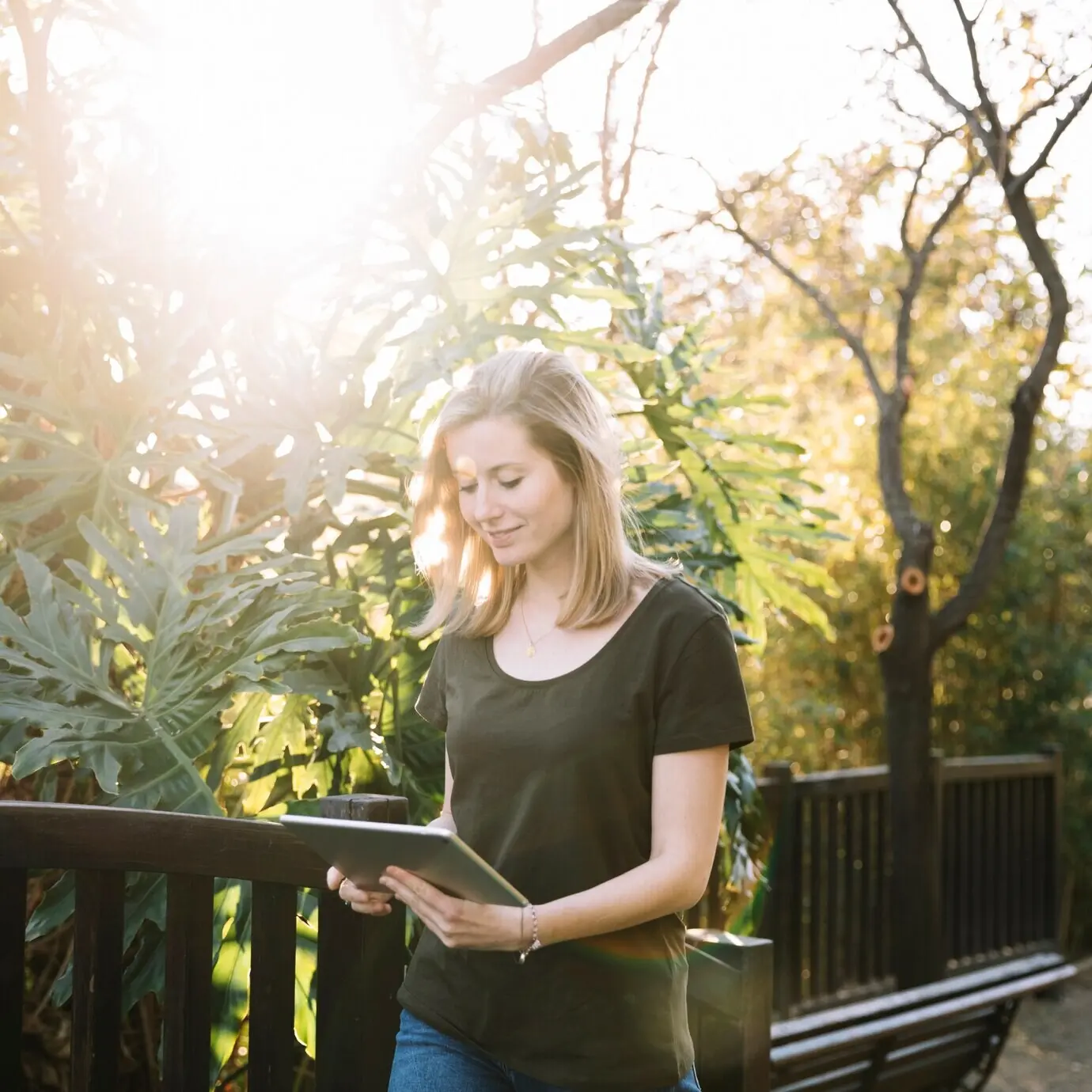 Charmante Frau mit Tablet, die im Park spaziert.